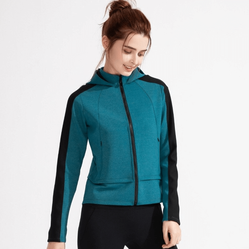 Woman wearing teal hooded sweatshirt with zipper and black accents, perfect for workouts, featuring thumb holes and long sleeves.